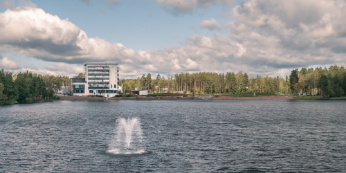 Järvi, jossa suihkulähde ja vastarannalla kerrostalo